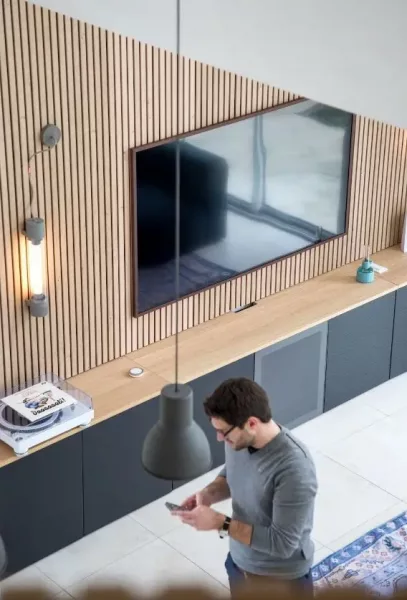 Personne utilisant un smartphone dans un bureau moderne avec des murs en bois et un écran mural